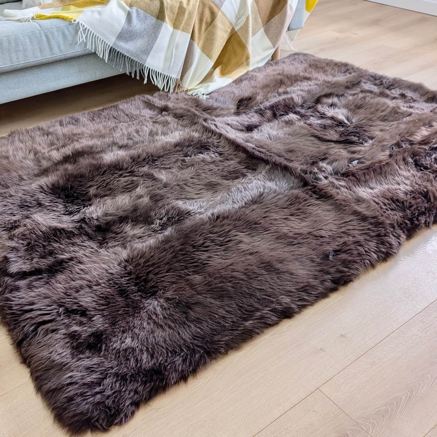 Covor Dreptunghiular din Blană Naturală de Oaie, Maro Ciocolatiu - mărime 180 x 120 cm - în fața canapelei