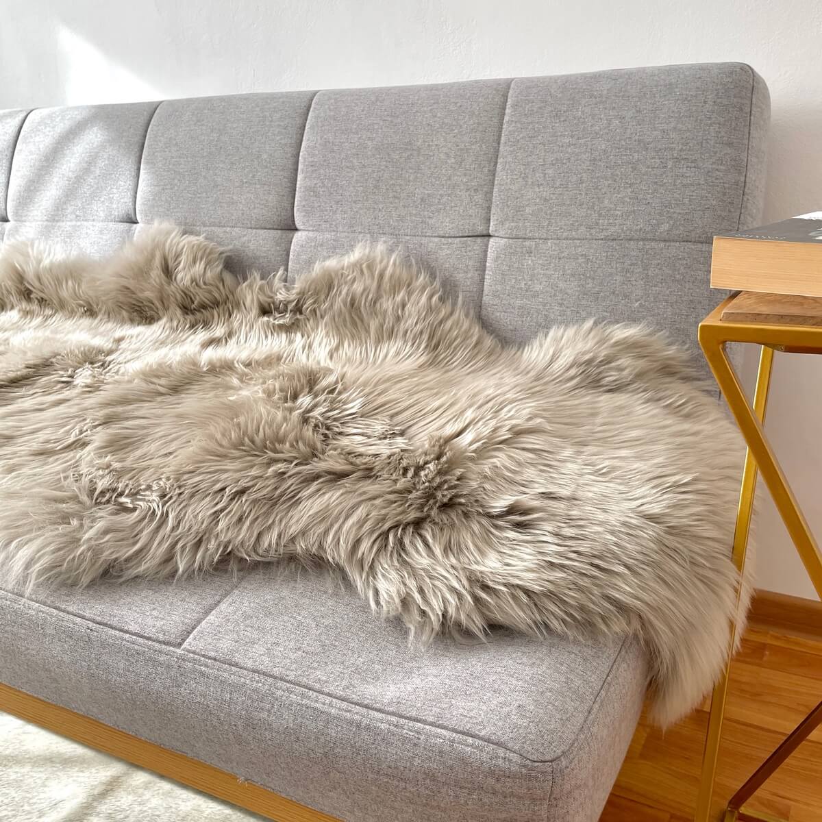 covor dublu din blana de oaie naturala, pufos si dens de culoare bej argintiu, pe canapea