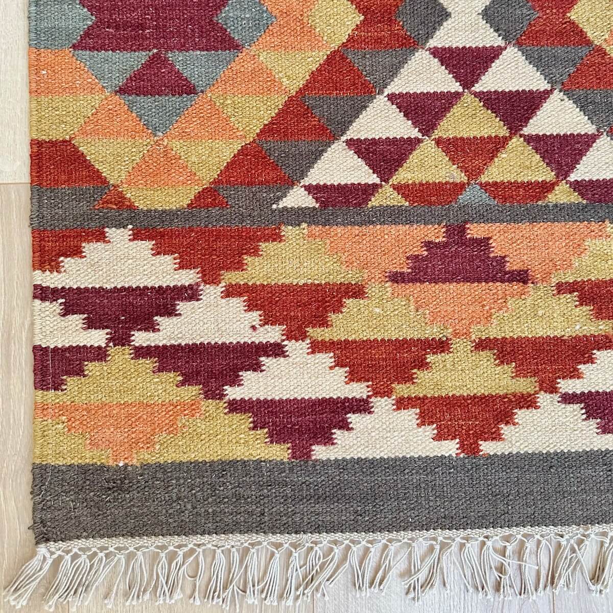 Covor subtire cu tesatura plata Kilim Alwar cu motive traditionale in culori calde de rosu maro si portocaliu in doua dimensiuni, model geometric in romb, colt