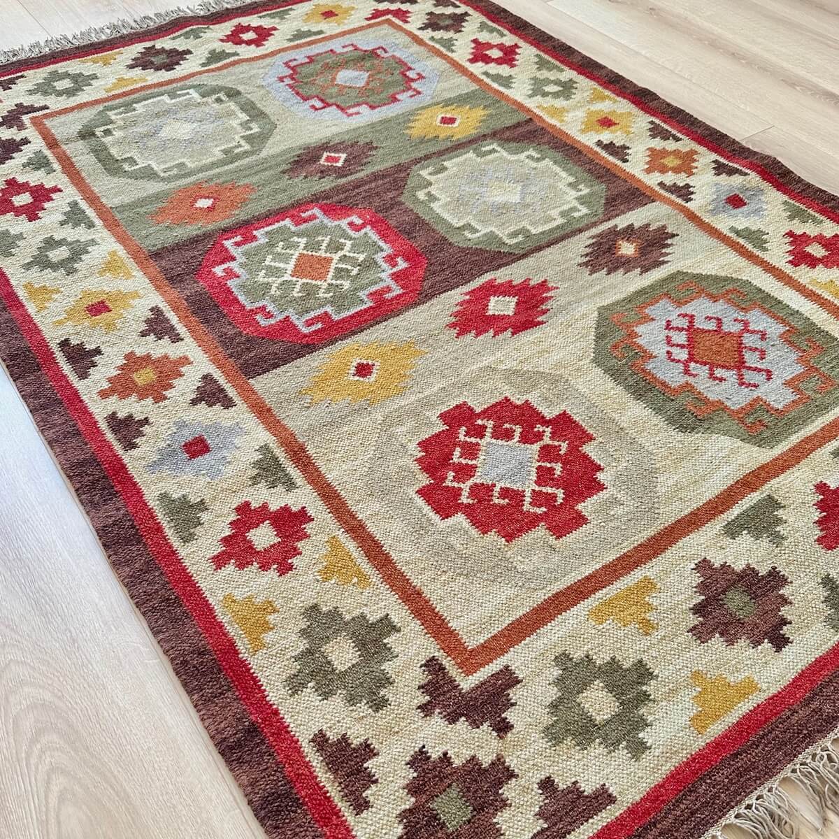 covor traditional kilim cu tesatura plata Kohra, model mic 120x180, multicolor nuante calde de maro rosu crem cu modele geometrice aztece, pe podea