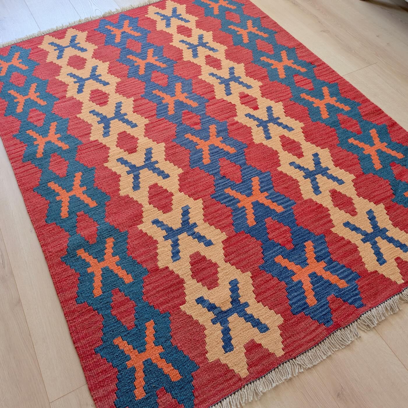 Covor din Lână Țesut Manual Plat - Kilim Gashghai (171cm x 126cm) - model geometric cu forme de X în culorile roșu, albastru și bej - pe podea