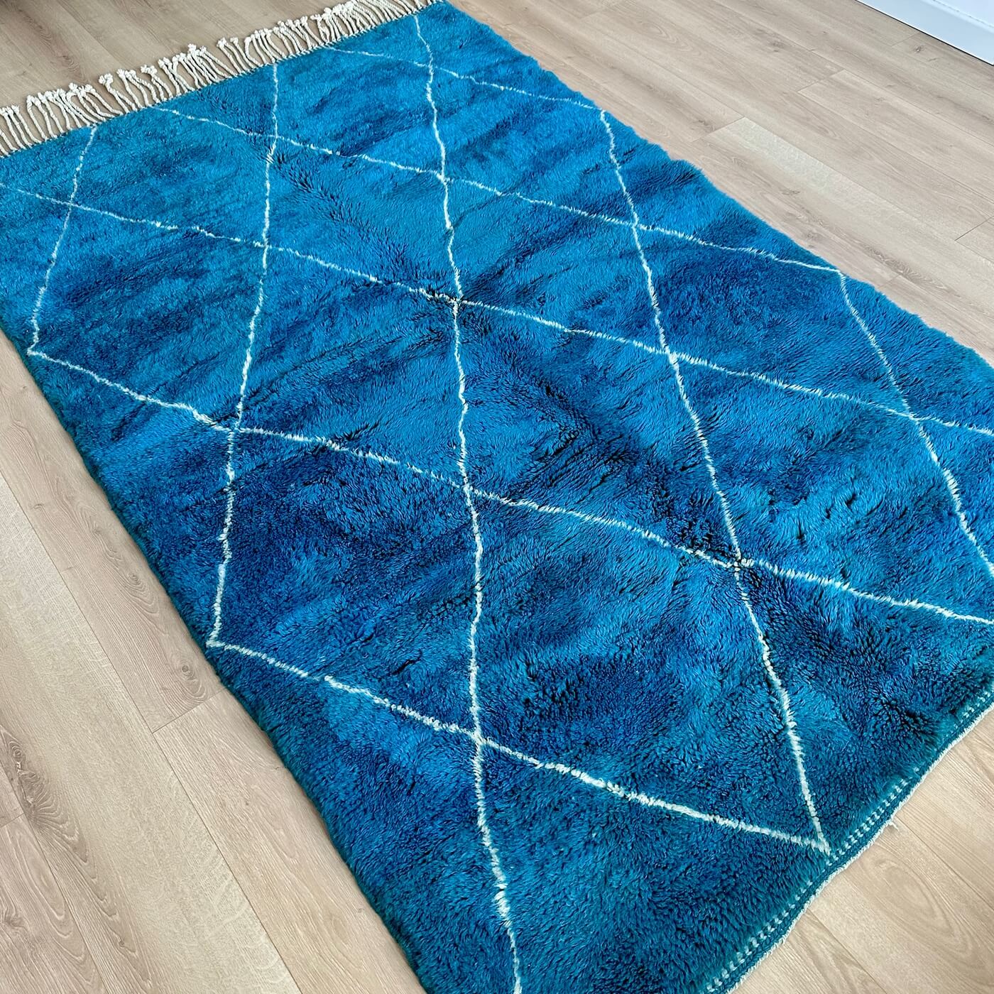 Covor gros și pufos din lână naturală realizat manual în Mrirt, Maroc. Perfect pentru living sau dormitor - dimensiune mare cu linii asimetrice albe pe un fundal albastru turcoaz - pe podea