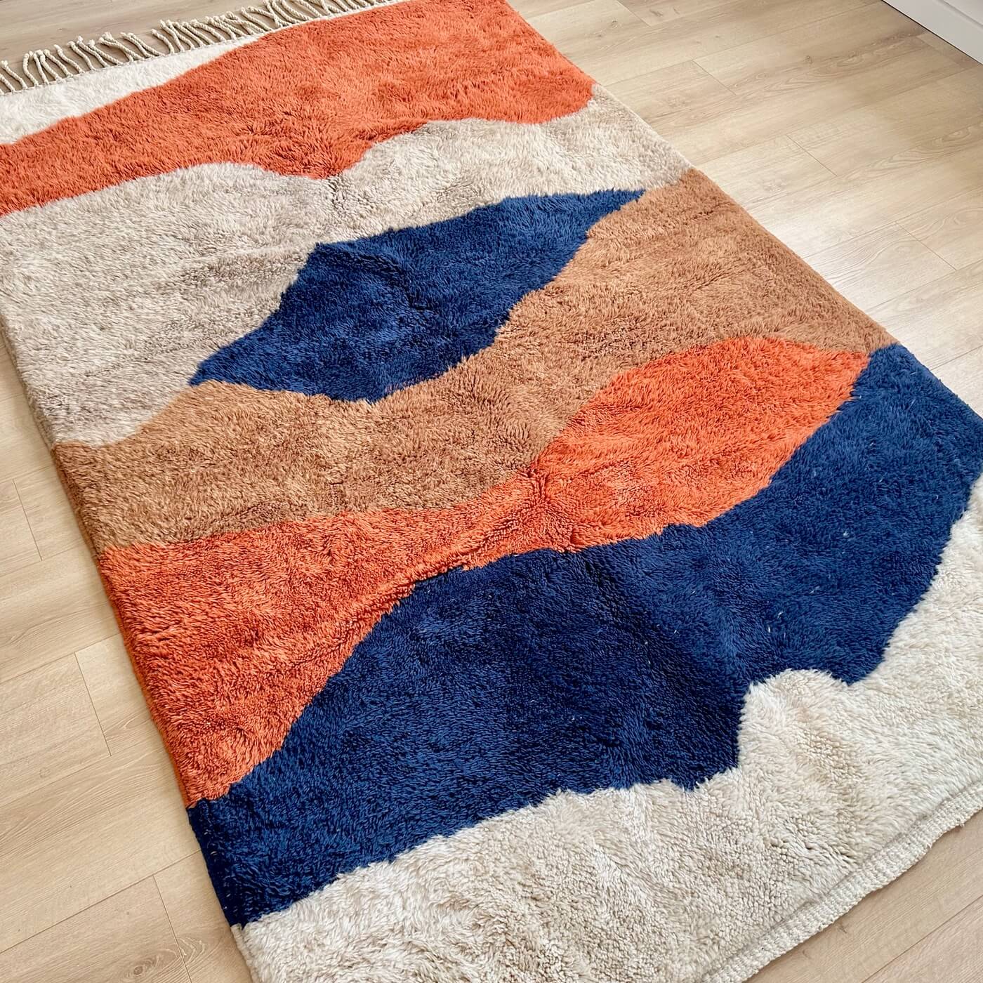 Covor modern gros și pufos din lână naturală realizat manual în Mrirt, Maroc. Perfect pentru living sau dormitor - dimensiune medie în culori de bej, maro, teracota si albastru - pe podea
