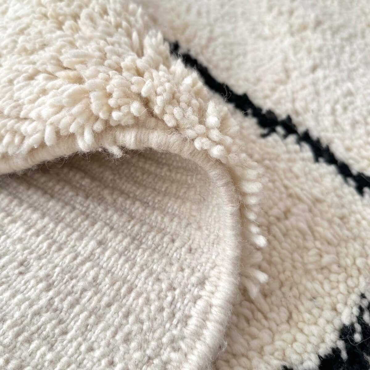 covor modern gros si pufos din lana creat manual in maroc, model alb cu dungi negre asimetrice, zoom