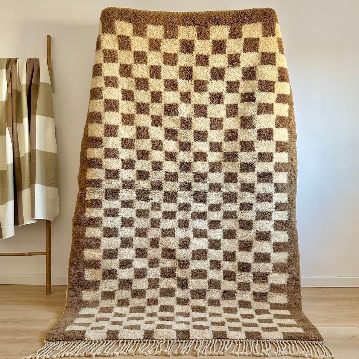 covor modern Berber Beni Mrirt innodat manual din lana organica de artizani din Maroc, model in carouri, dens pufos si luxos, in picioare langa patura