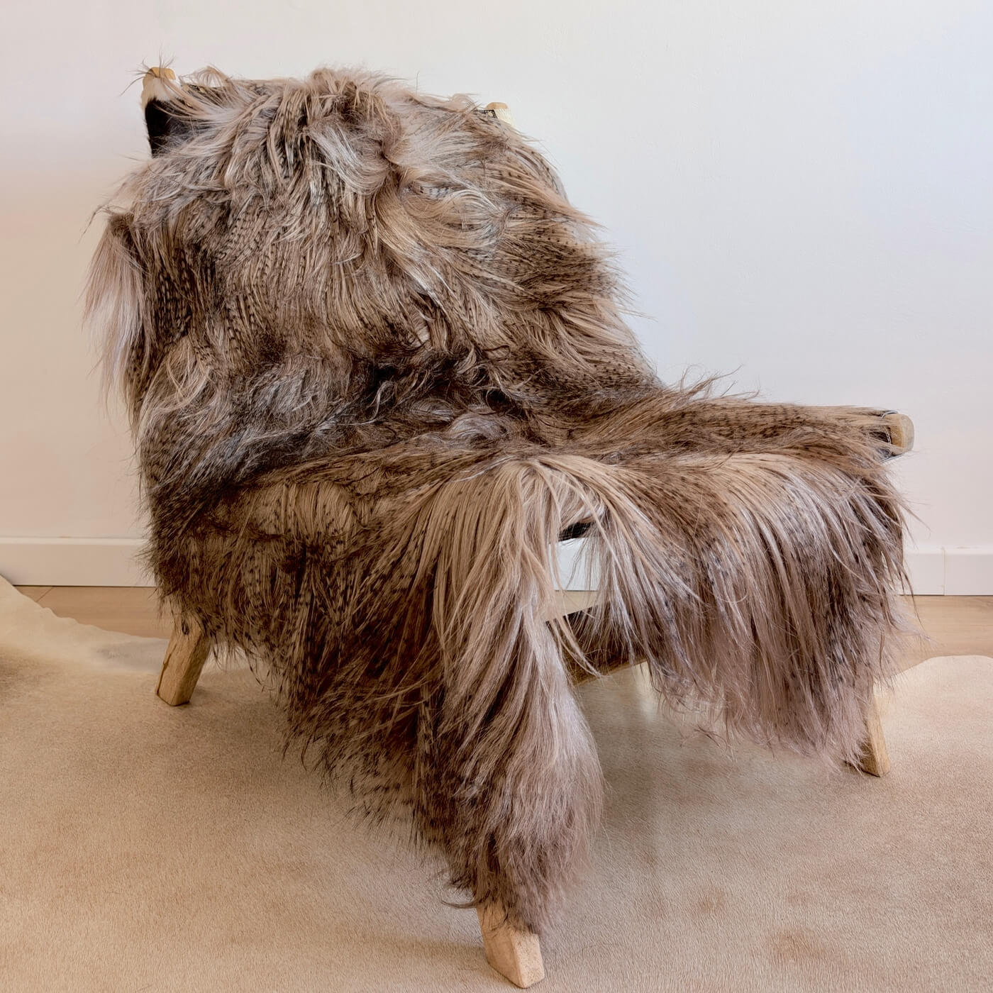 Covor din piele naturala de capra mongola cu fir extra lung si ondulat, nuanta gri maroniu, pe fotoliu