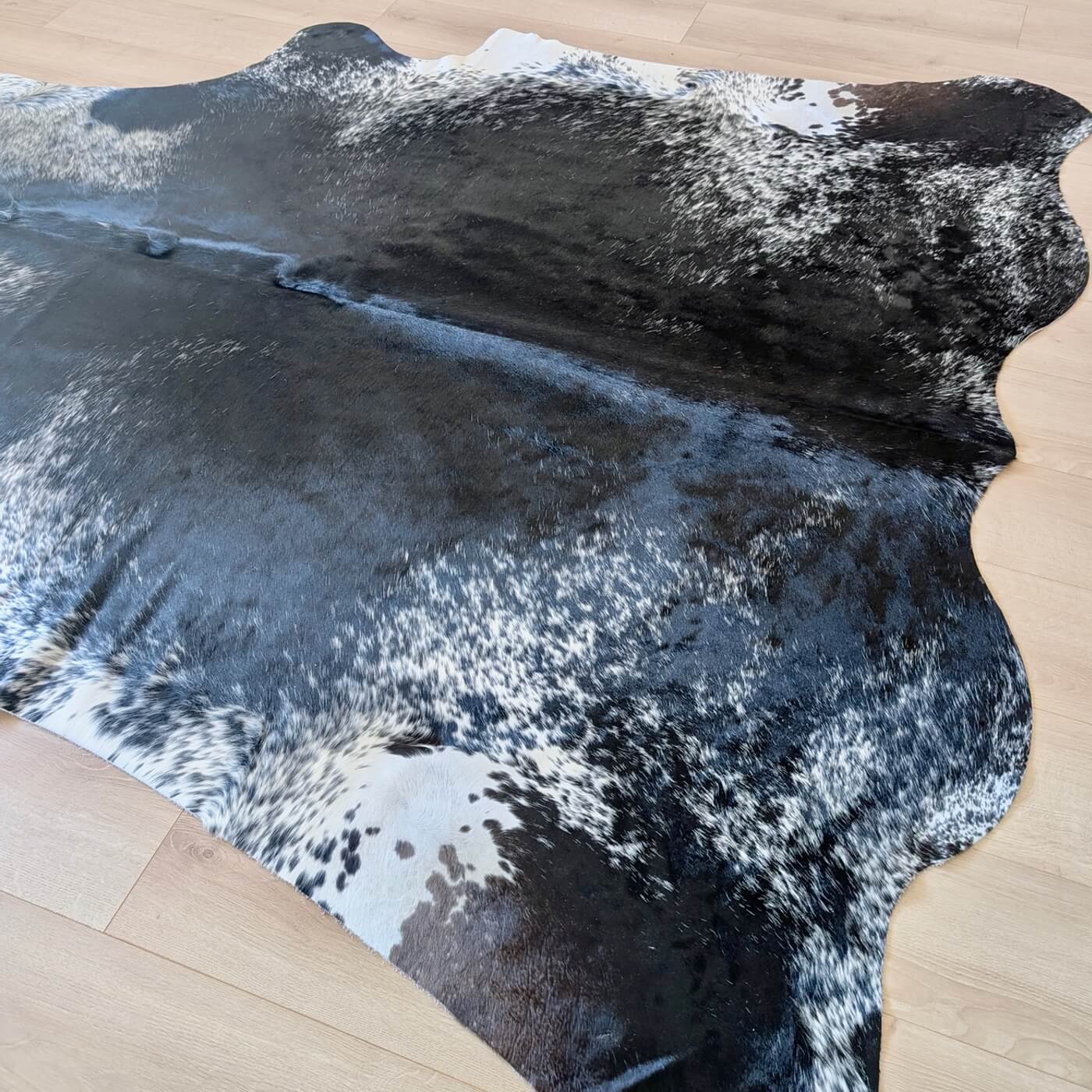 covor din piele de vaca pestrit cu fundal negru si detalii albe si gri - perfect pentru living, studio sau birou - baza