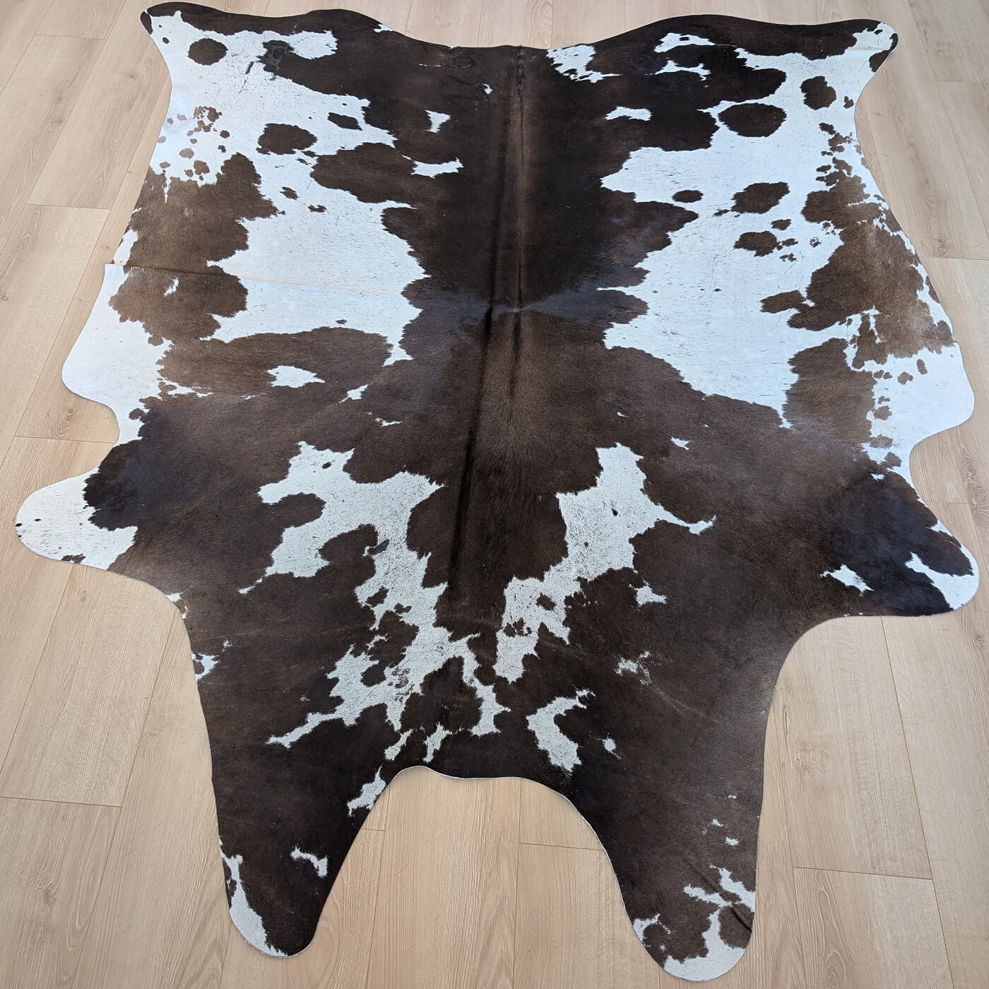 covor din piele de vaca maro inchis cu alb mbch526 pe parchet