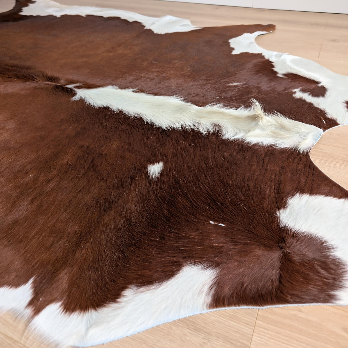 covor din piele naturala de vaca in culori maro cu alb pe parchet, mango+bloom