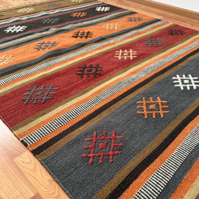 covor kilim Juma tesut traditional din lana si bumbac, culori si nuante pamantii calde cu modele, pe parchet