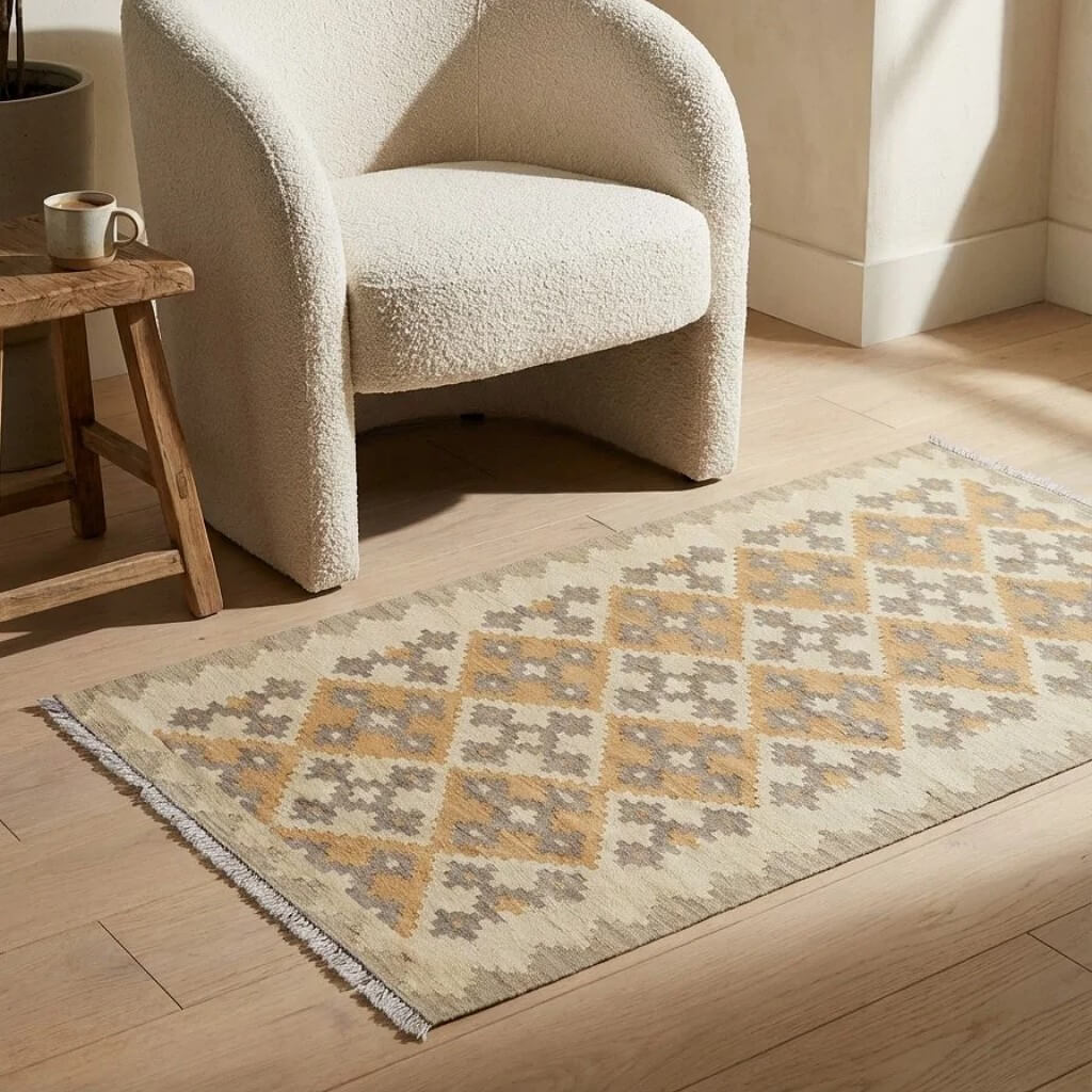 Covor traversa din lana tesut manual in stil traditional Kilim Gashghai (198cm x 85cm) in nuante de bej si gri in fata unui fotoliu pe parchet
