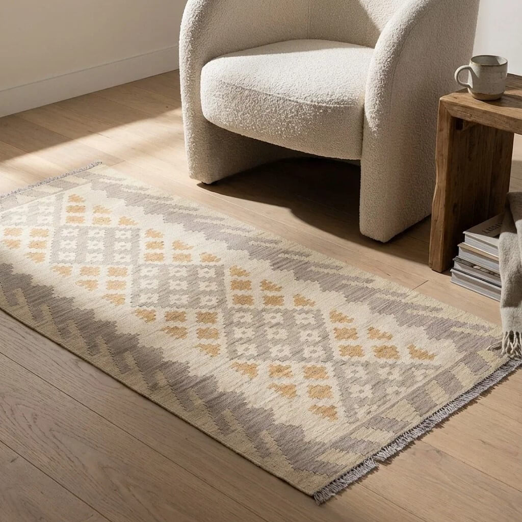 Covor traversa din lana tesut manual Kilim Gashghai (197cm x 84cm) in nuante de bej si gri in fata unui fotoliu