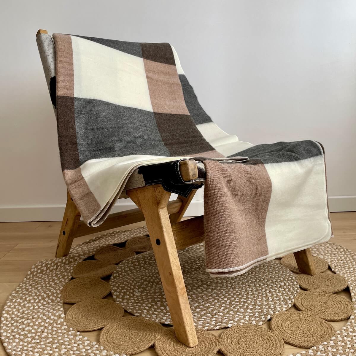 patura reversibila din lana de alpaca model in carouri, nunate de gri maro, pe scaun