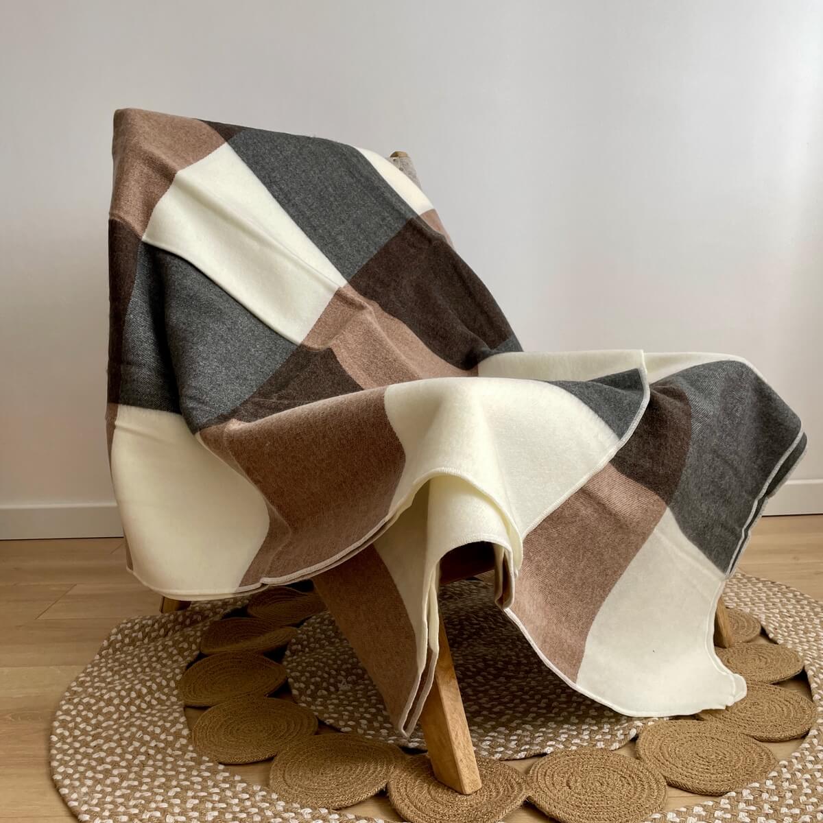 patura reversibila din lana de alpaca model in carouri, nunate de gri maro, pe scaun intinsa