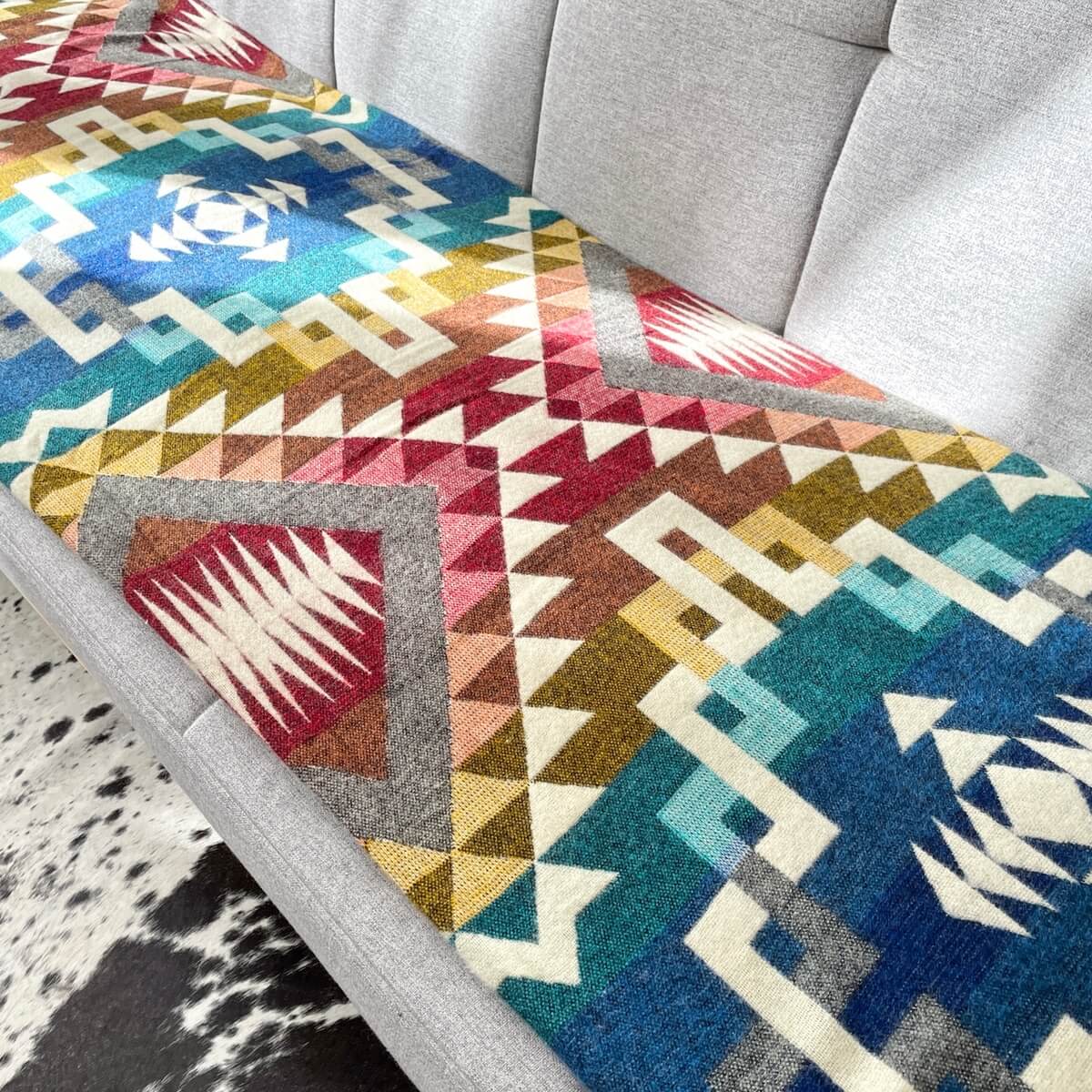 patura reversibila din lana de alpaca pufoasa si moale Guayaquil, multicolora, pe canapea