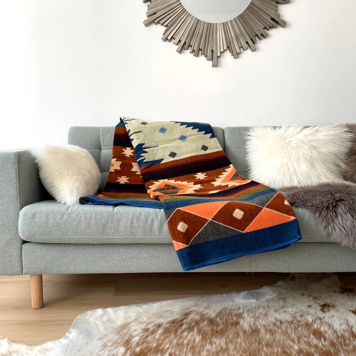 patura din lana de alpaca cu forme aztece in nuante multicolore quilotoa albastru pe canapea