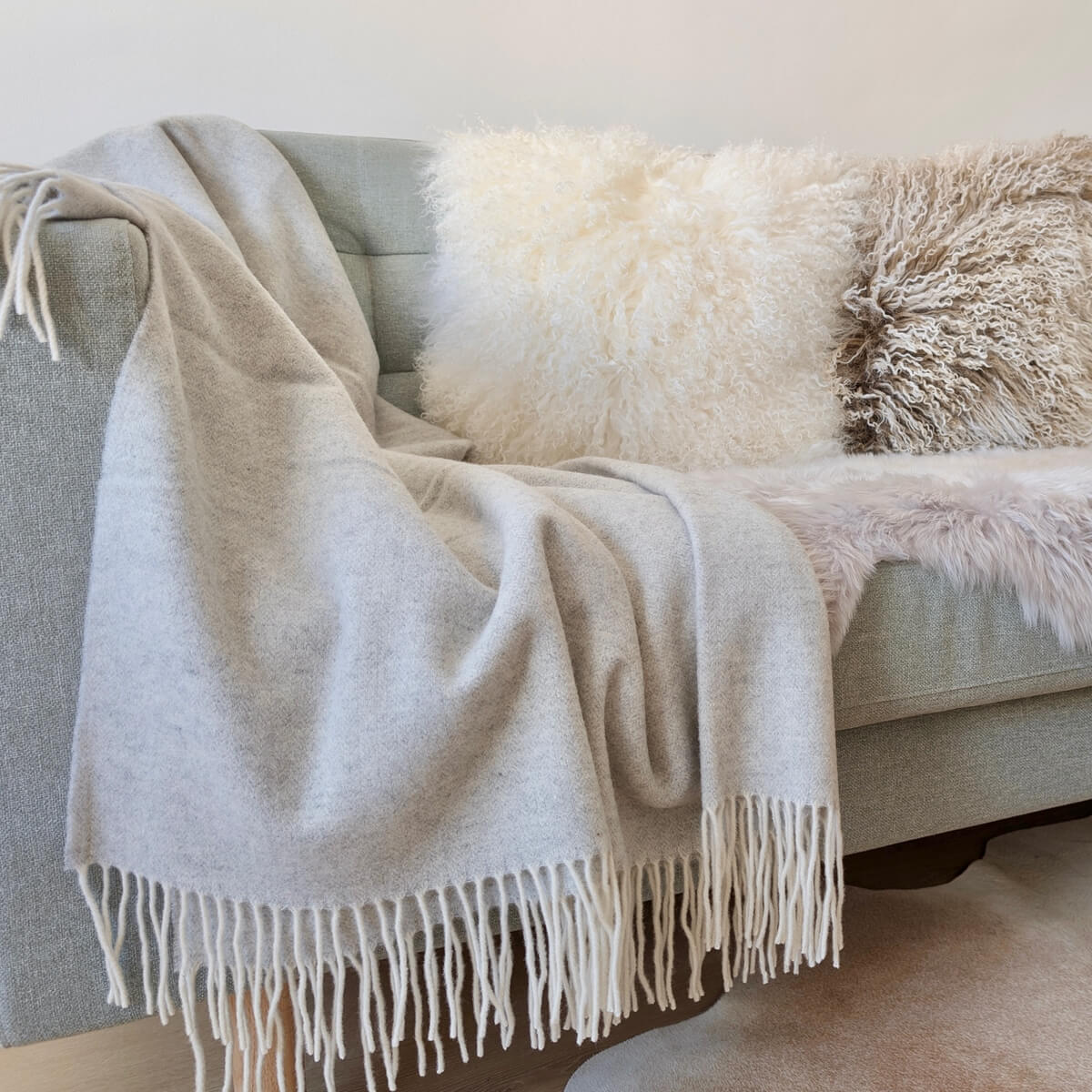 Patura Milano realizata din 90% lana merino si 10% casmir, functioneaza atat ca patura pentru canapea cat si ca cuvertura de pat, design modern gri, pe canapea