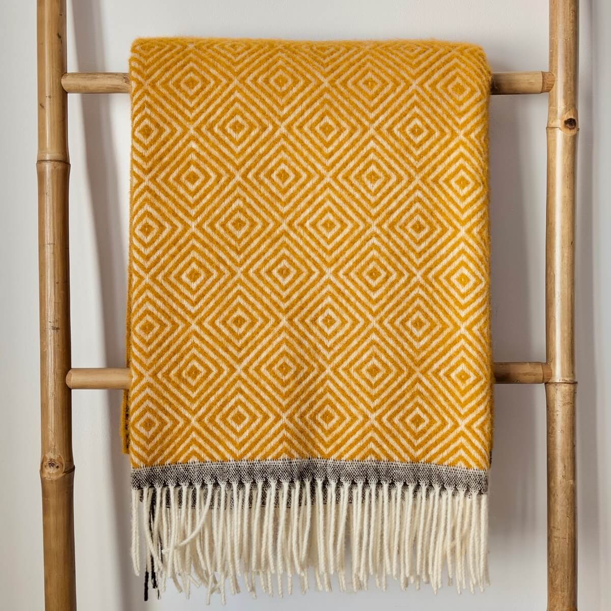 Patura groasa Venezia realizata 100% din lana de Noua Zeelanda, design modern cu romburi albe si ciucuri pe ambele parti, pe scara