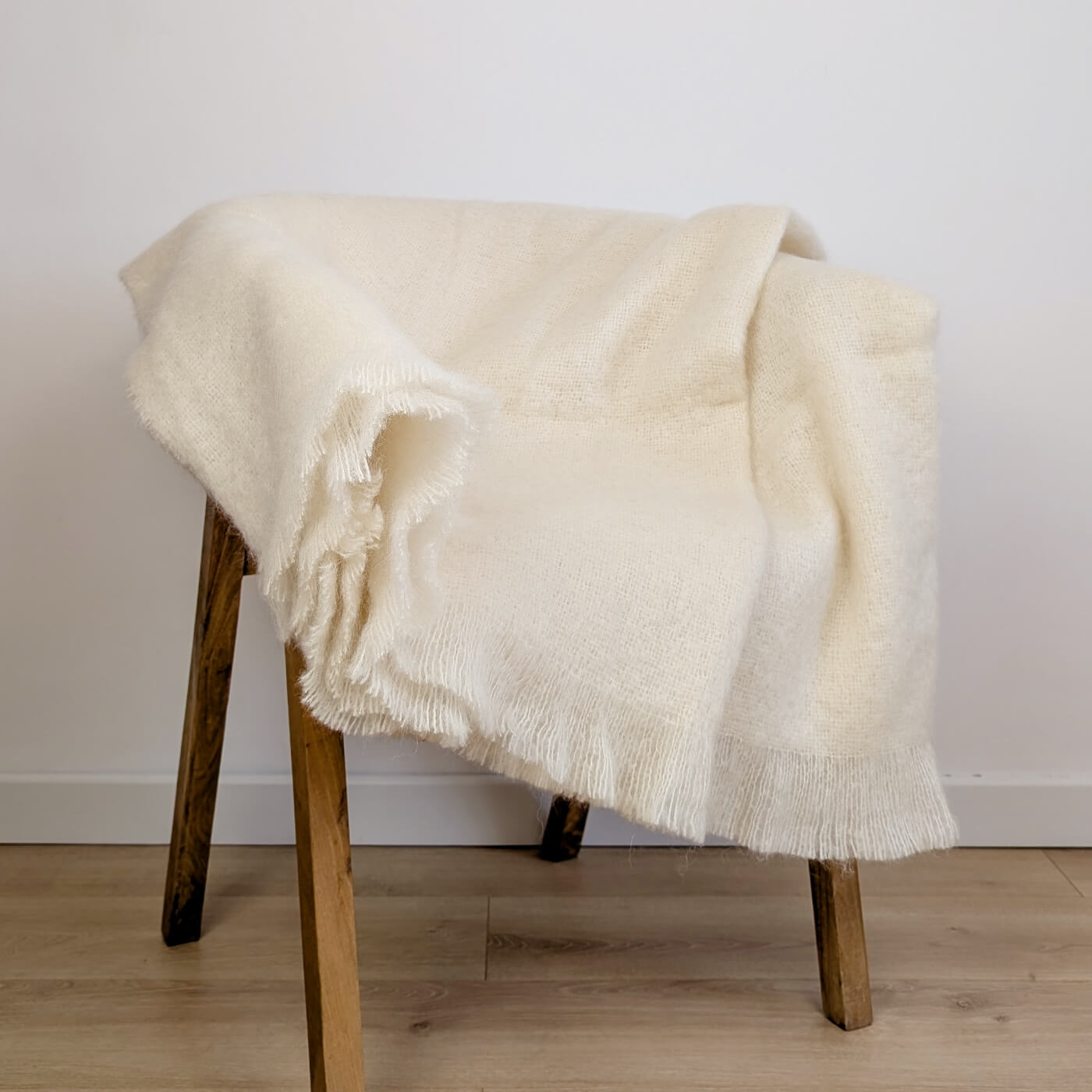 Pătură din mohair superfin model simplu într-o singură culoare alb-gălbui, pe scaun