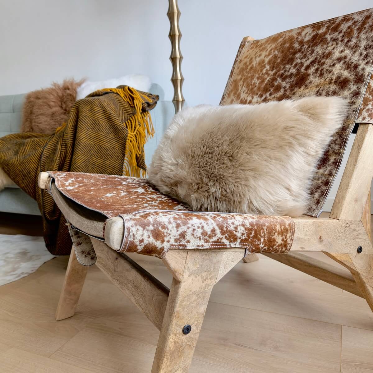 fotoliu lounge din lemn si piele de vaca cu o perna decorativa din blana naturala, decor de casa