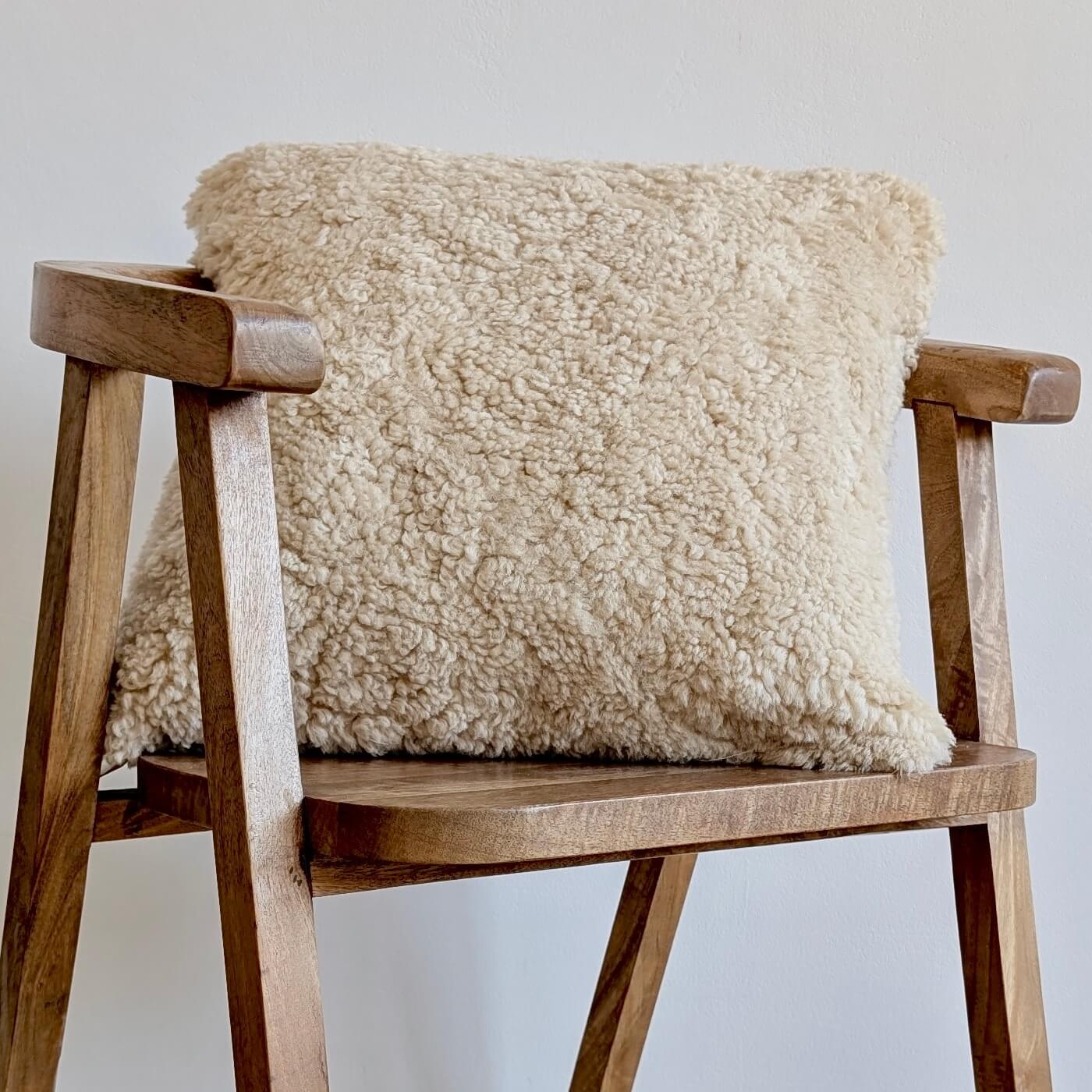 Perna Decorativa Pătrată 45x45 cm - din Blana de Oaie Australiana Scurta Creata, Bej Moonlight - pe scaun de lemn