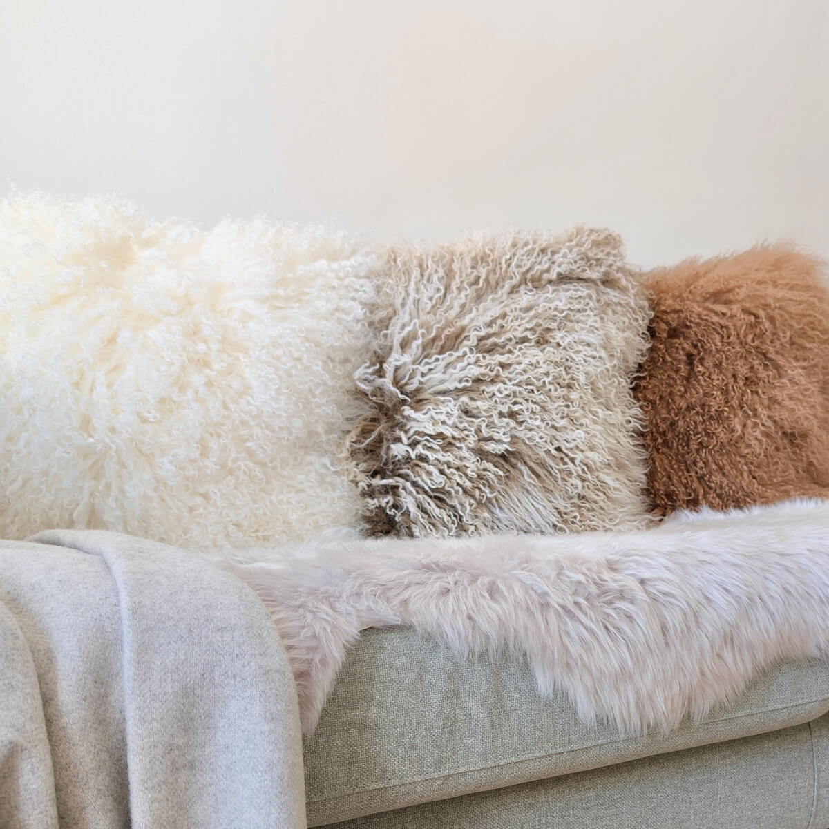 perne decorative din blana de oaie cu fir lung incretit, pe canapea, nuante calde