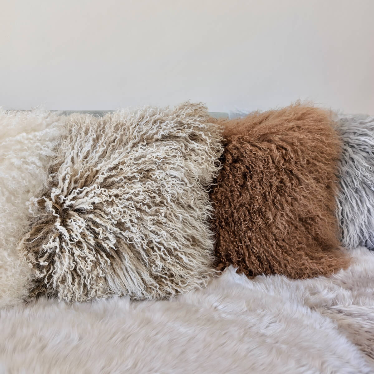 perne decorative din blana de oaie cu fir lung incretit, pe canapea