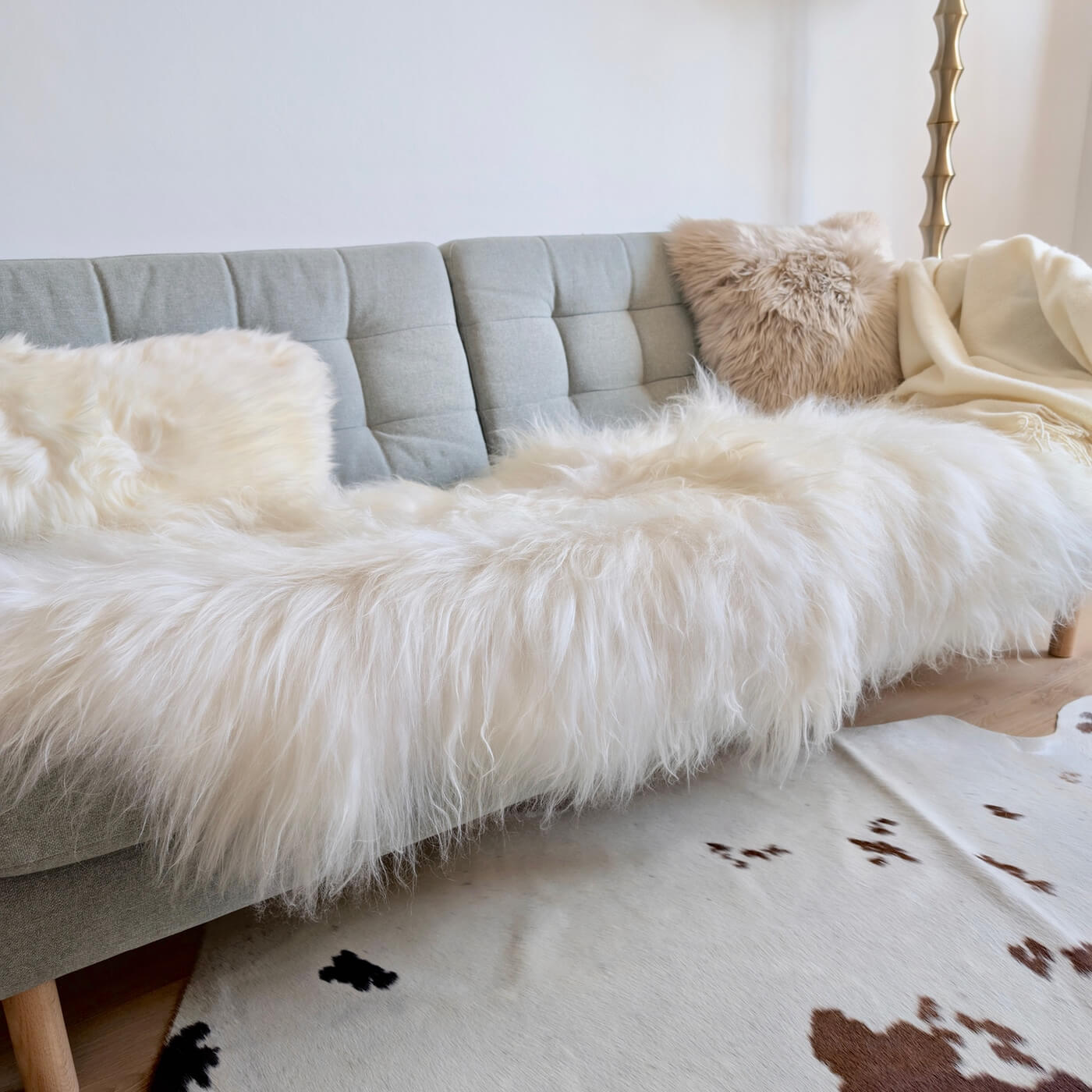Covor dublu din blană naturală de oaie islandeză - realizat din 2 piei întregi cusute împreună - dimensiune 180 x 70 cm și fir extra lung de minim 10 cm în nuanță de alb ivory - pe canapea