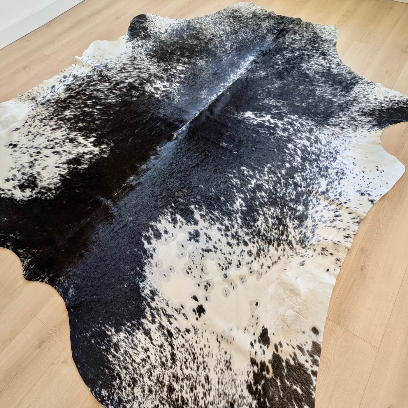 Covor din Piele de Vacă - Negru Pestriț (280cm x 250cm) - model pestrit fundal negru si pete albe gri - mărime XXXL - pe parchet în living