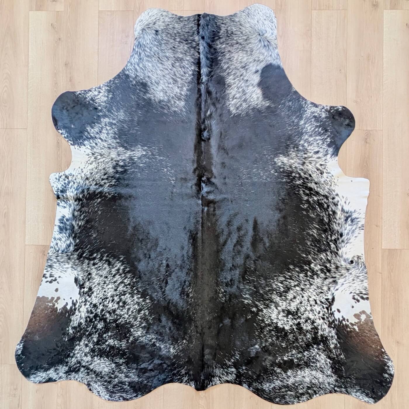 covor din piele de vaca pestrit cu fundal negru si detalii albe si gri - perfect pentru living, studio sau birou - de sus