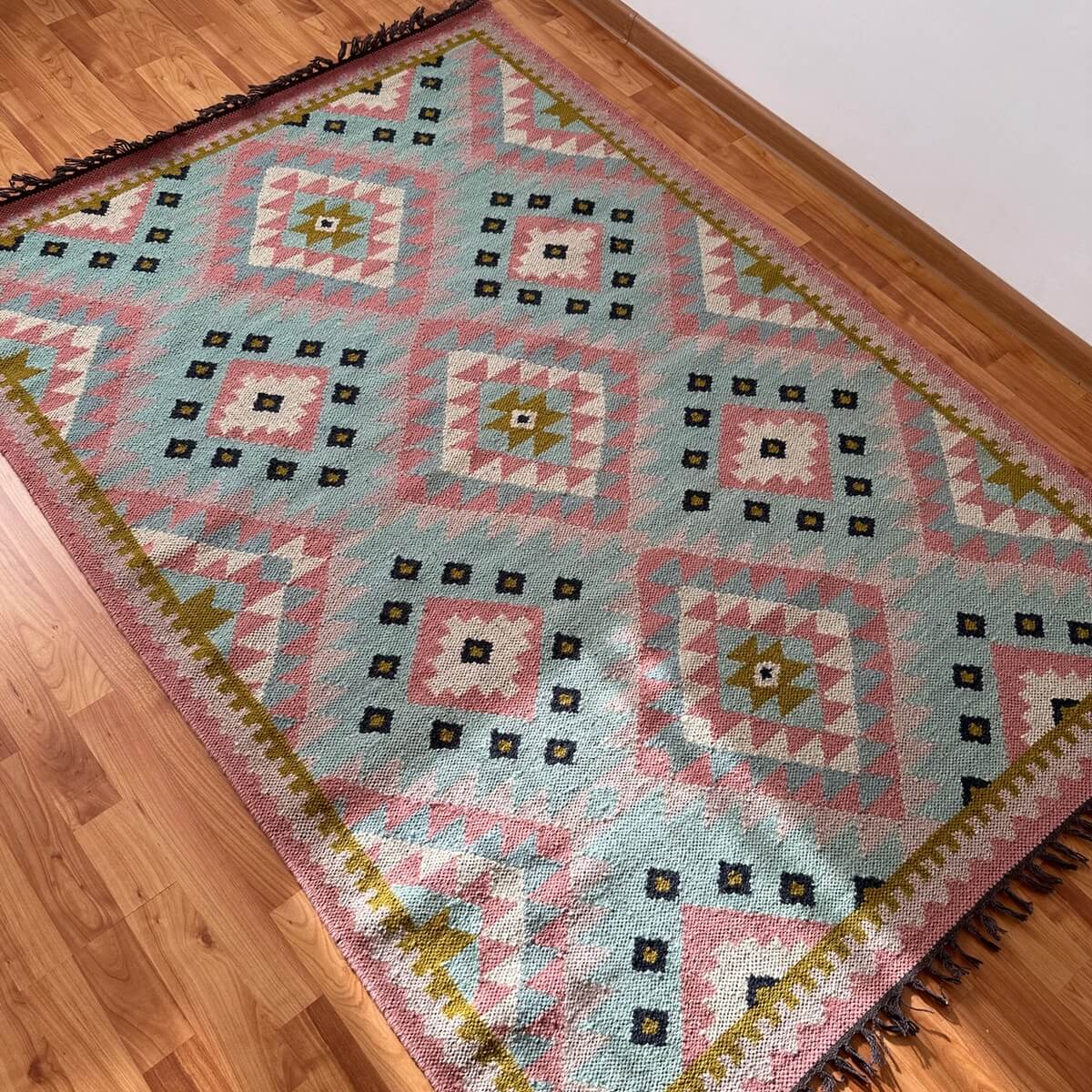 covor traditional kilim Jovita tesut manual 100% din lana, model geometric in romb in culori roz si turcoaz, pe podea
