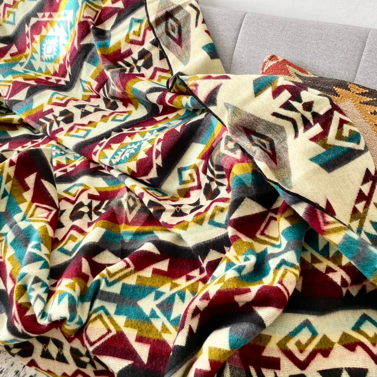 patura reversibila din lana de alpaca chimborazo model multi colora, aruncata pe canapea