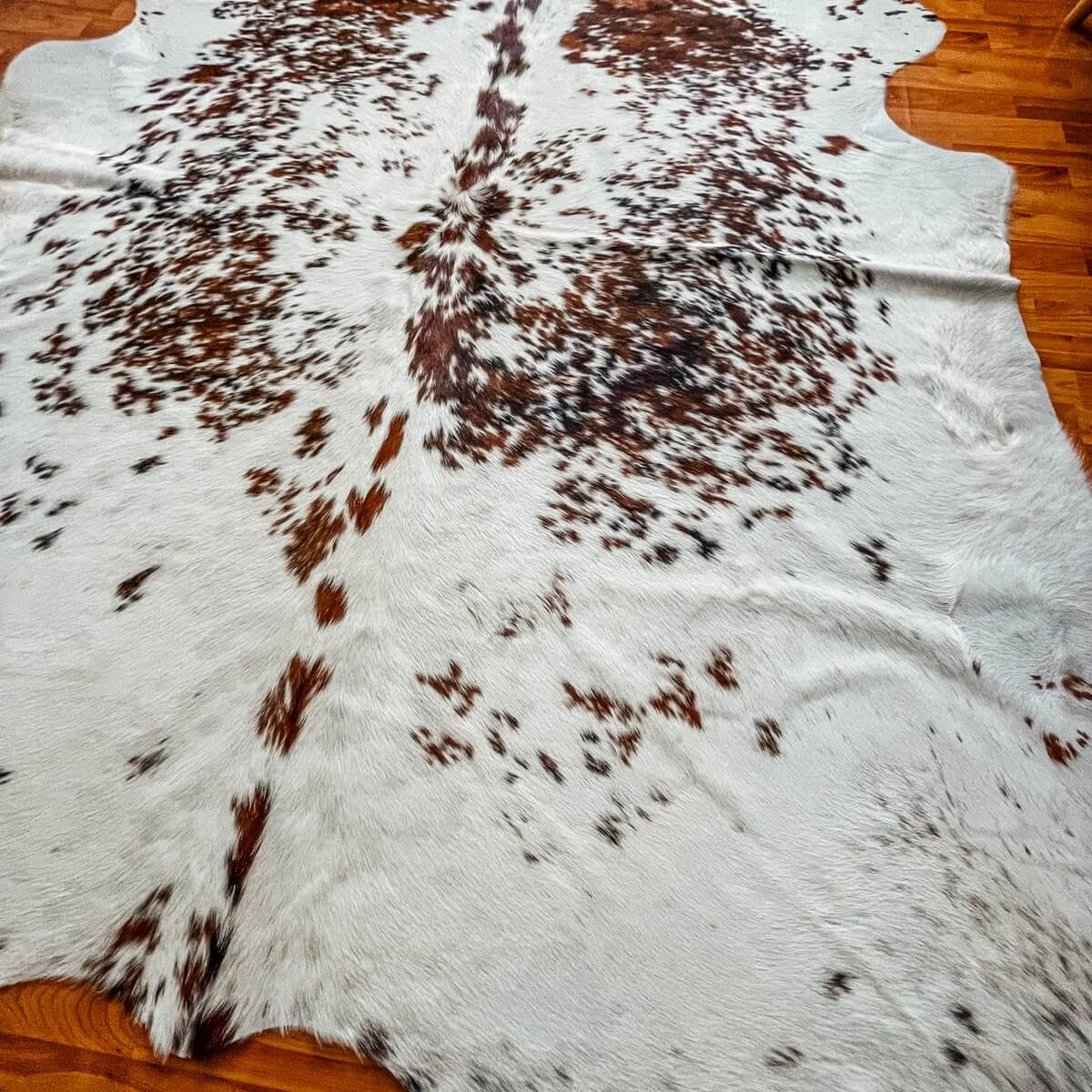 covor din piele de vaca alb pestrit nuante maro, pe podea
